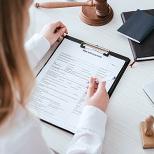 A woman diligently writing on a legal document related to immigration protections for undocumented individuals in Texas. - R. Ramirez Attorneys and Counselors